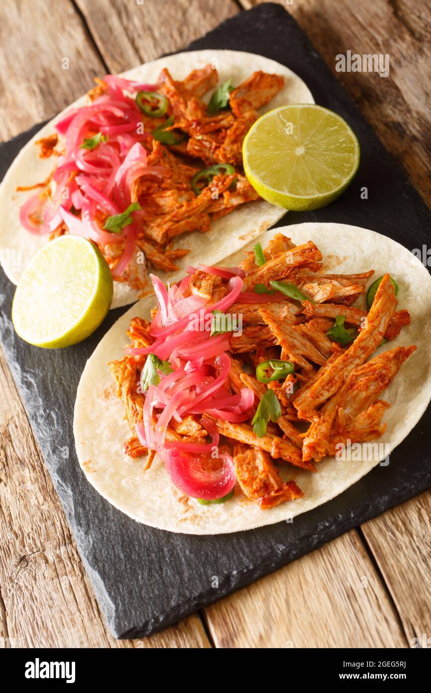 Mexican Cochinita pibil is an easy braised pork dish served with tortilla and pickled onion closeup in the slate board on the table. Vertical Stock Photo