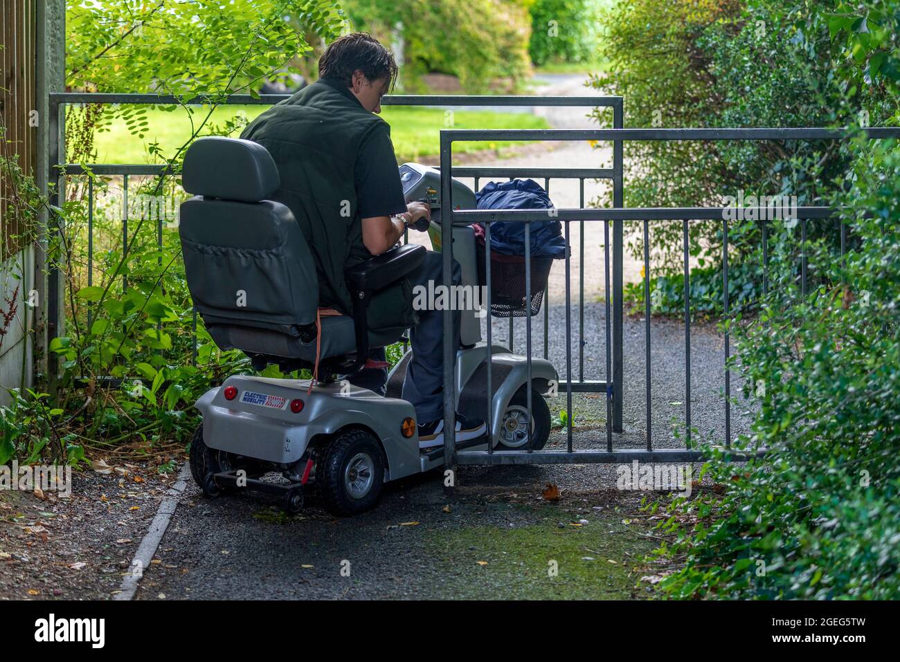 Negotiating an difficult cycle gate on a disability mobility scooter Stock  Photo - Alamy