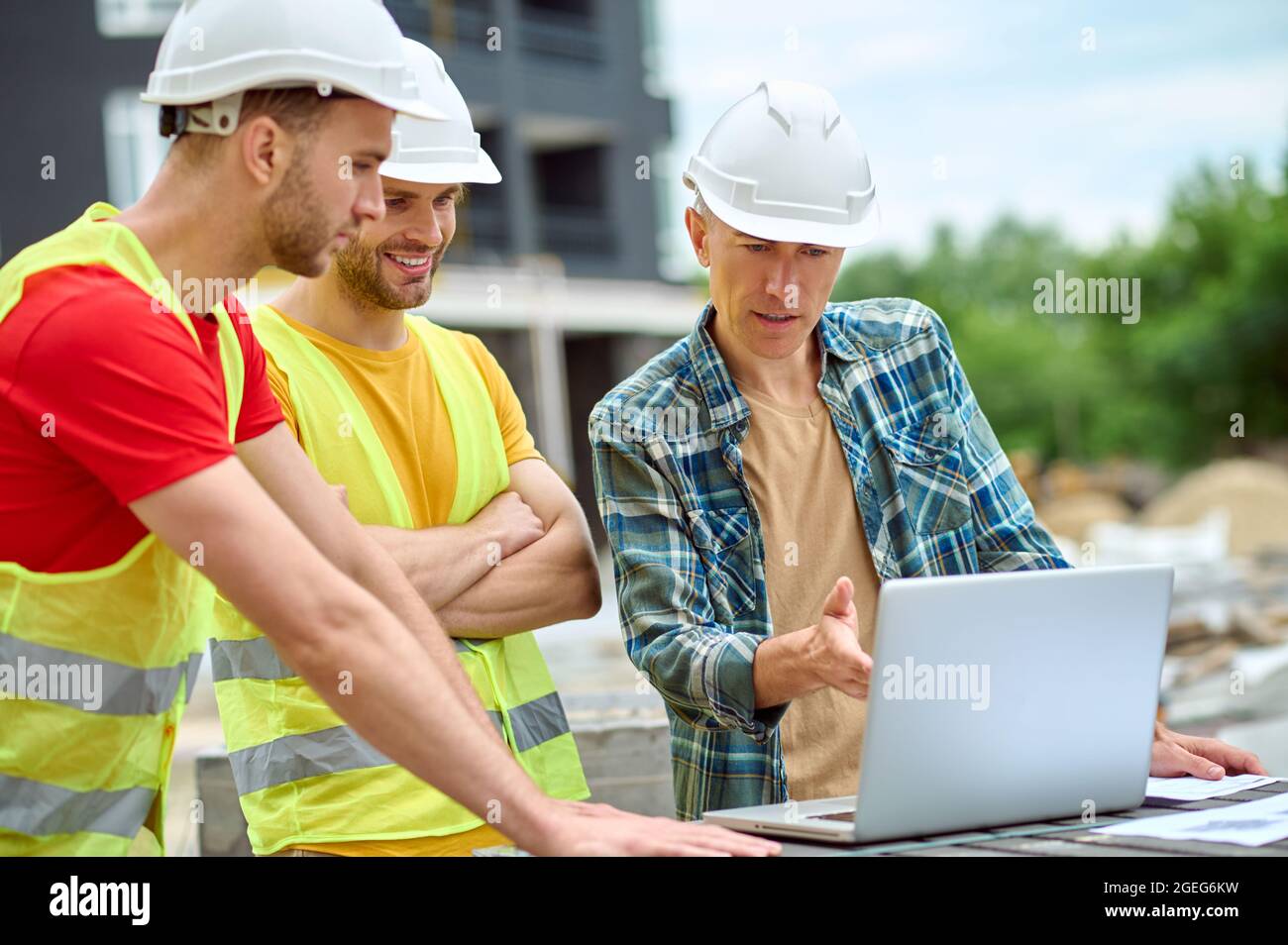 Three colleagues discussing a new building project outdoors Stock Photo