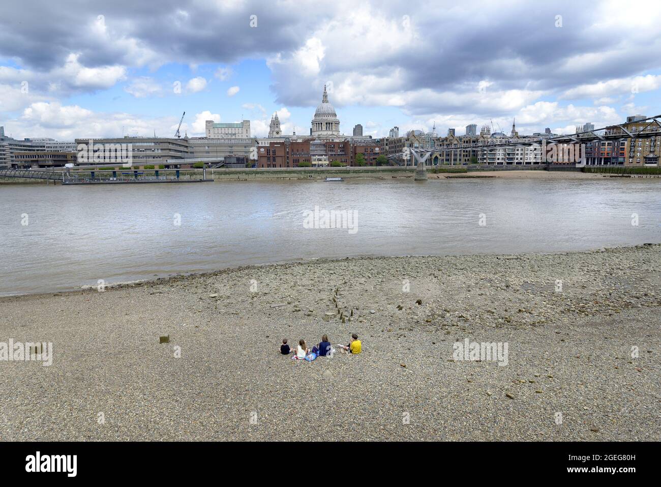 London, England, UK. People on the beach on the South Bank of the River Thames at low tide, looking towards St Paul's Cathedral and the City of London Stock Photo