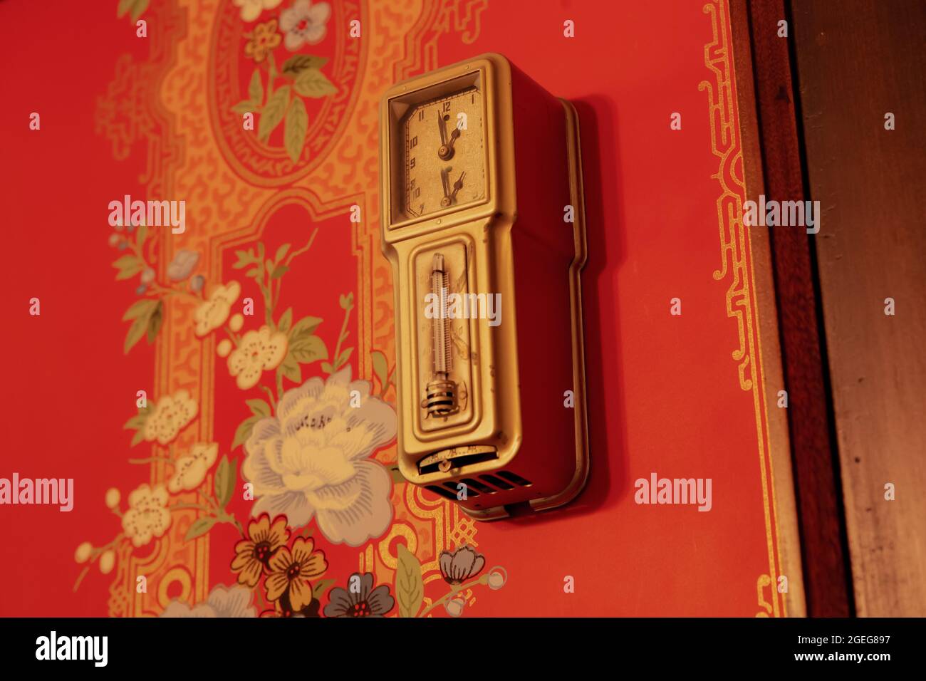Old vintage clock on a red painted wall with flowers Stock Photo - Alamy
