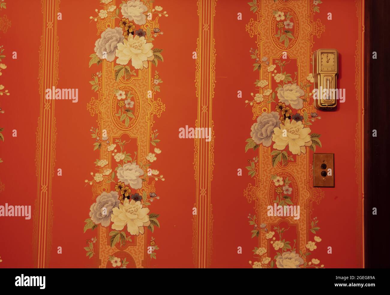 Old vintage clock on a red painted wall with flowers Stock Photo - Alamy