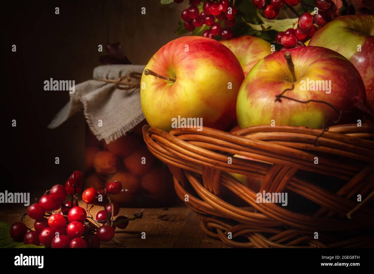 apples and branches of viburnum on a dark wooden background in a rustic ...
