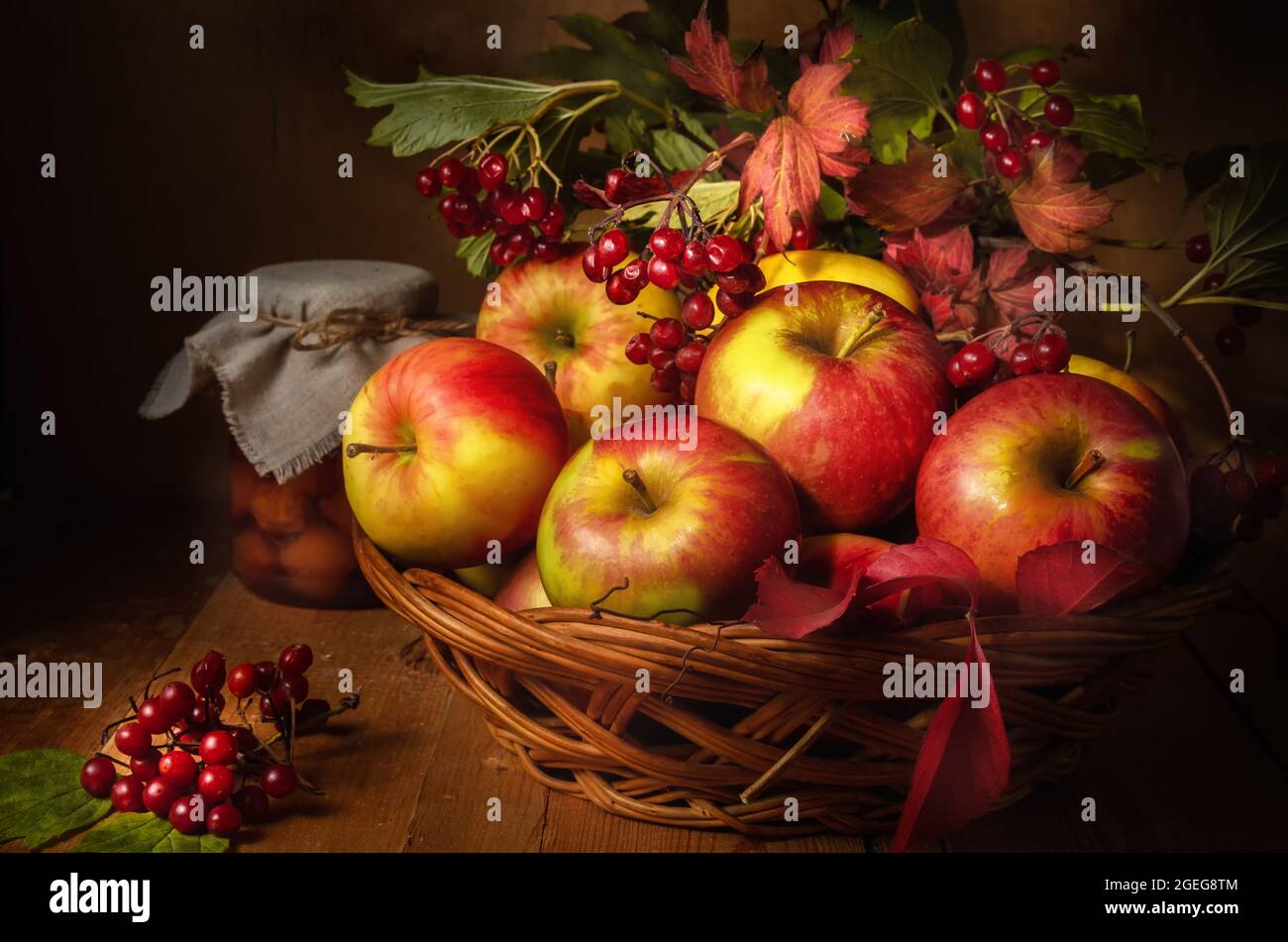 apples and branches of viburnum on a dark wooden background in a rustic ...