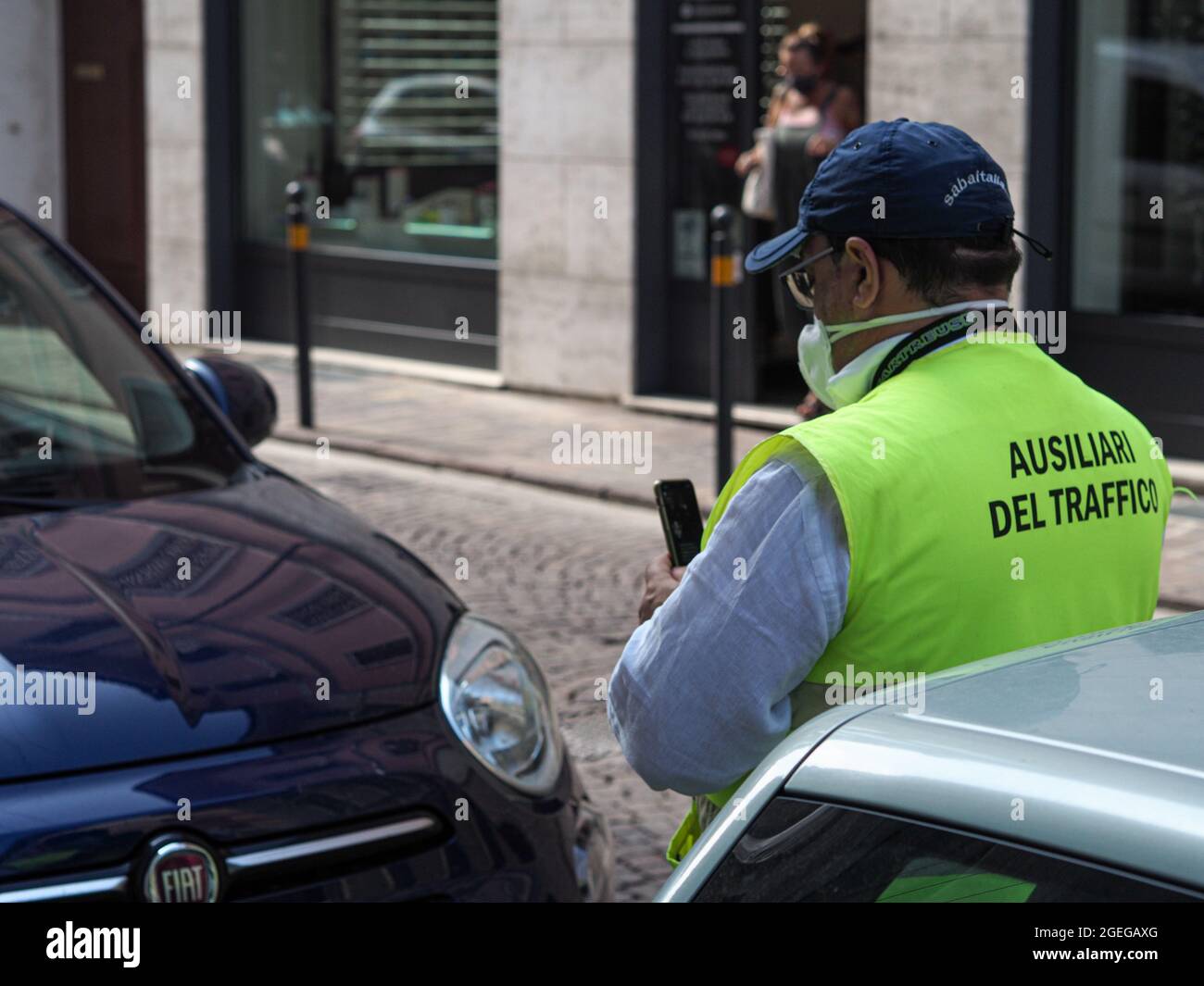 LOMBARDY, ITALY - Aug 19, 2021: Parking attendant verifying online and issuing printing parking fine in the str Stock Photo