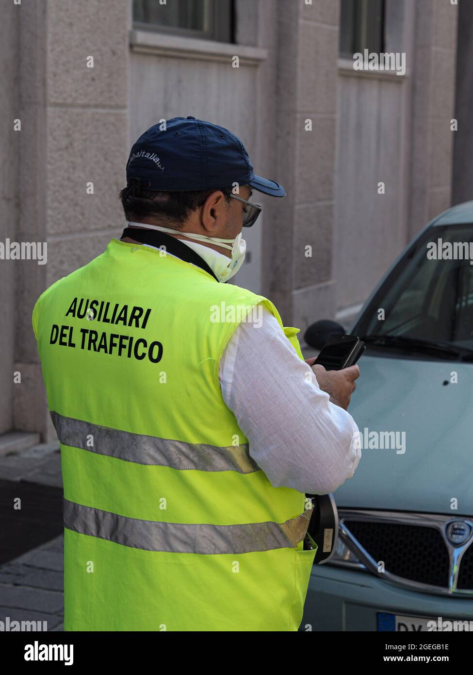 LOMBARDY, ITALY - Aug 19, 2021: Parking attendant verifying online and issuing printing parking fine in the str Stock Photo