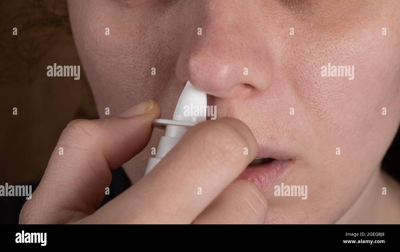 remedy for the common cold, the girl puffs a nasal spray in the nose. Stock Photo