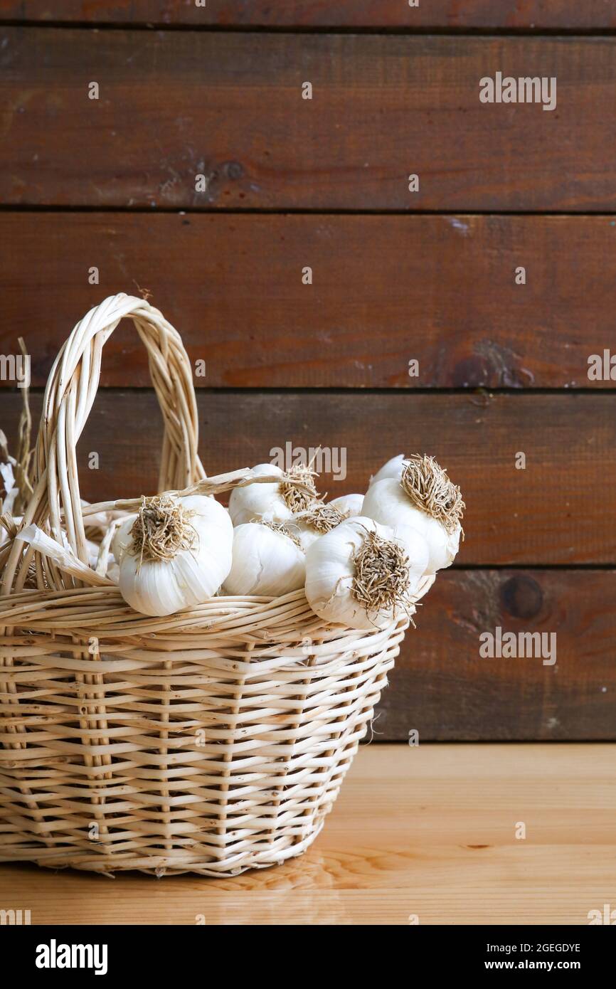 a basket of dried garlic in front of a wooden background, writing area Stock Photo