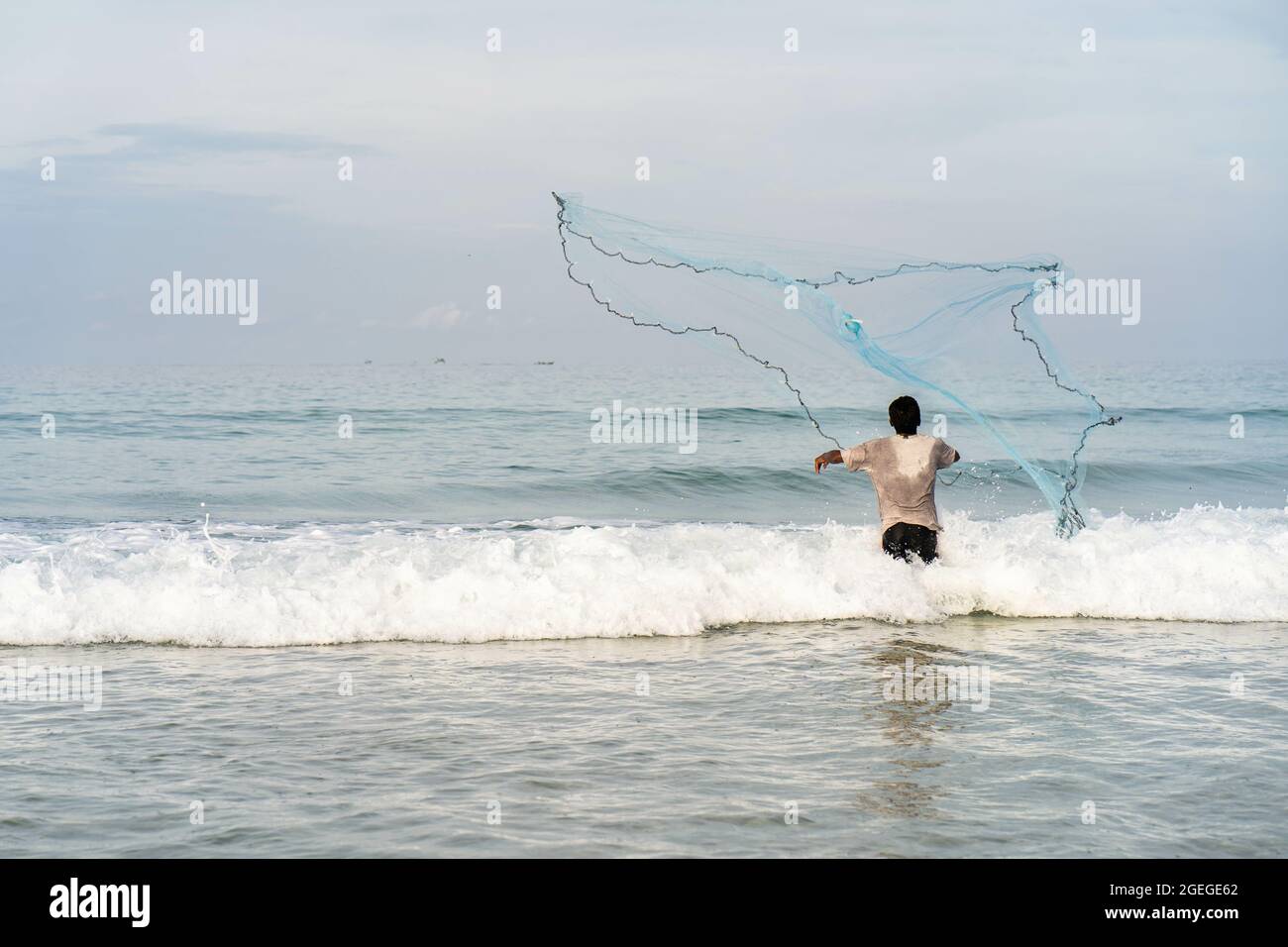 Fisherman standing on the shore and throwing a fishing net into