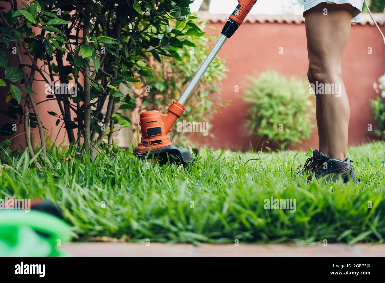 woman using the brushcutter cutting the lawn Stock Photo