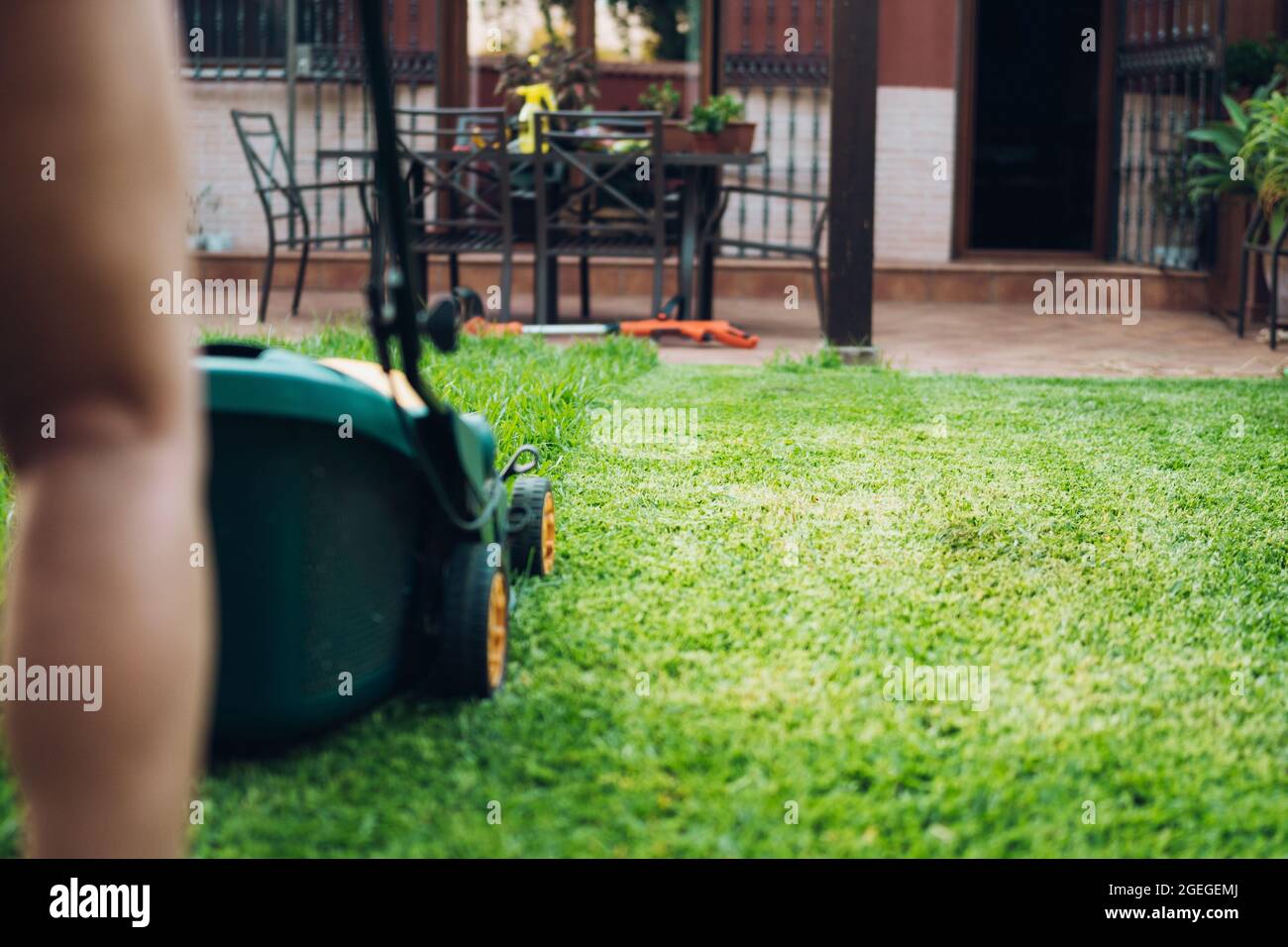 unrecognizable person using lawn mowers in his garden Stock Photo