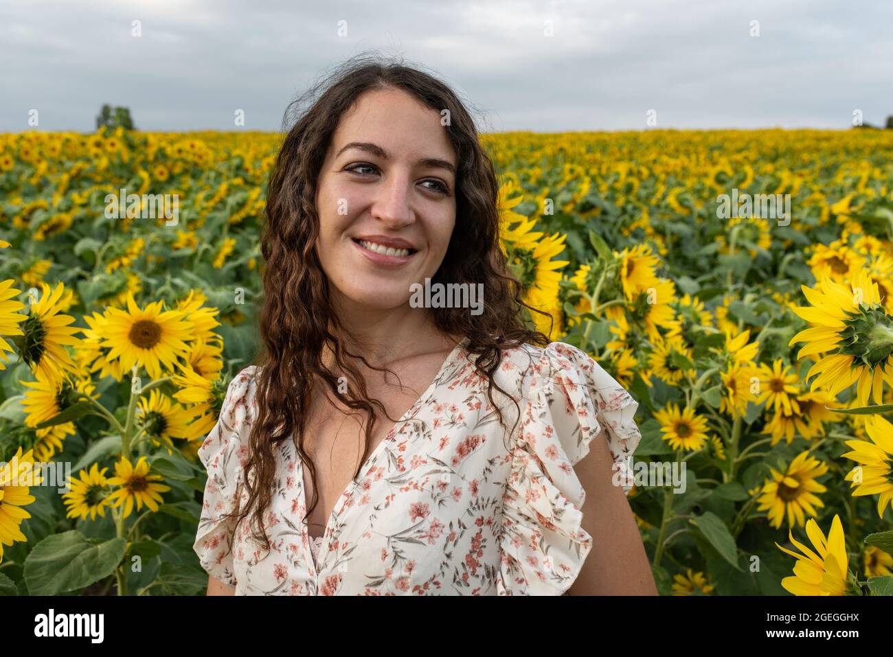 Young woman standing in the middle of a field of sunflowers Stock Photo ...