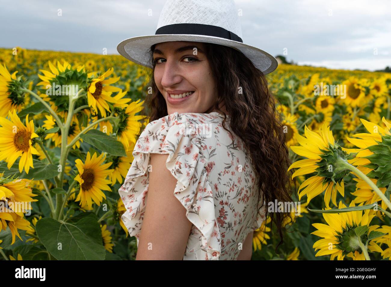 Young woman standing in the middle of a field of sunflowers Stock Photo ...