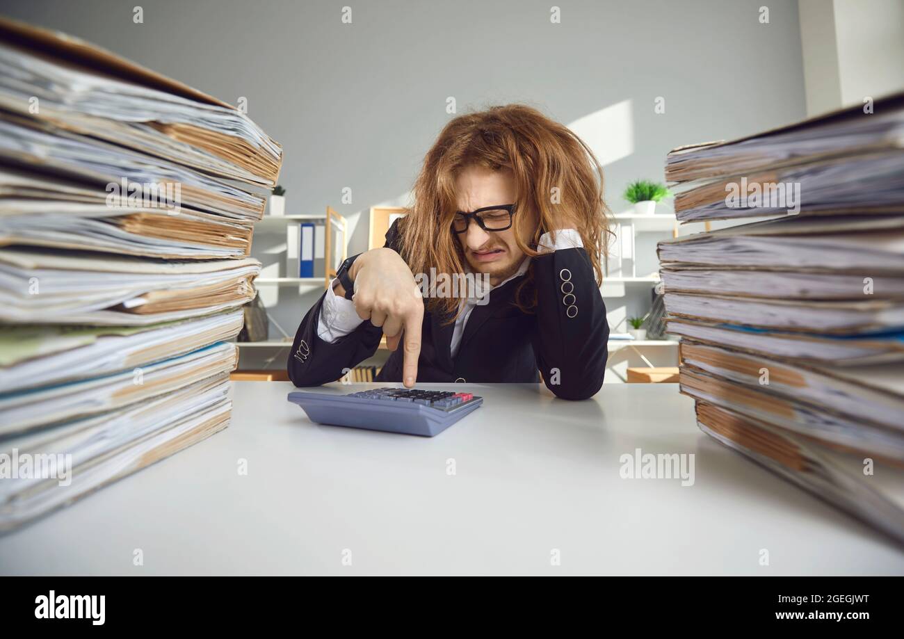 Funny young weird man accountant financial worker counting on calculator Stock Photo