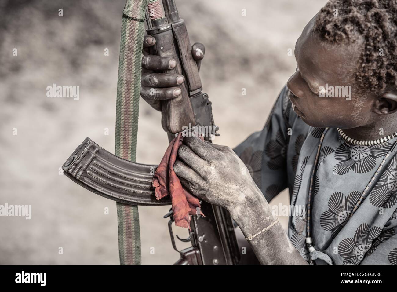 Maintaining and cleaning the guns is an important aspect of keeping them functional. TEREKEKA, SOUTH SUDAN: In one image, a man stared into the camera Stock Photo
