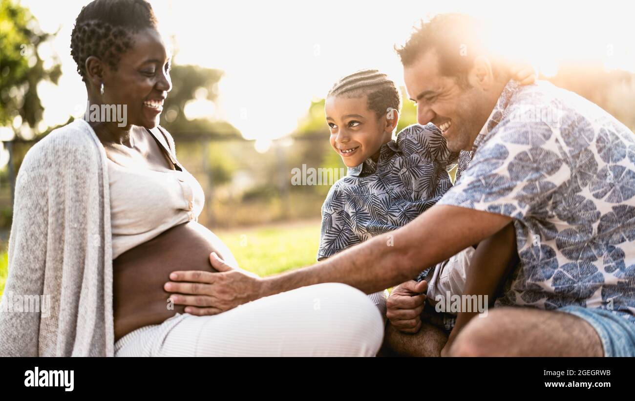 Happy multiracial family having fun together in park during sunset time - Focus on child face Stock Photo