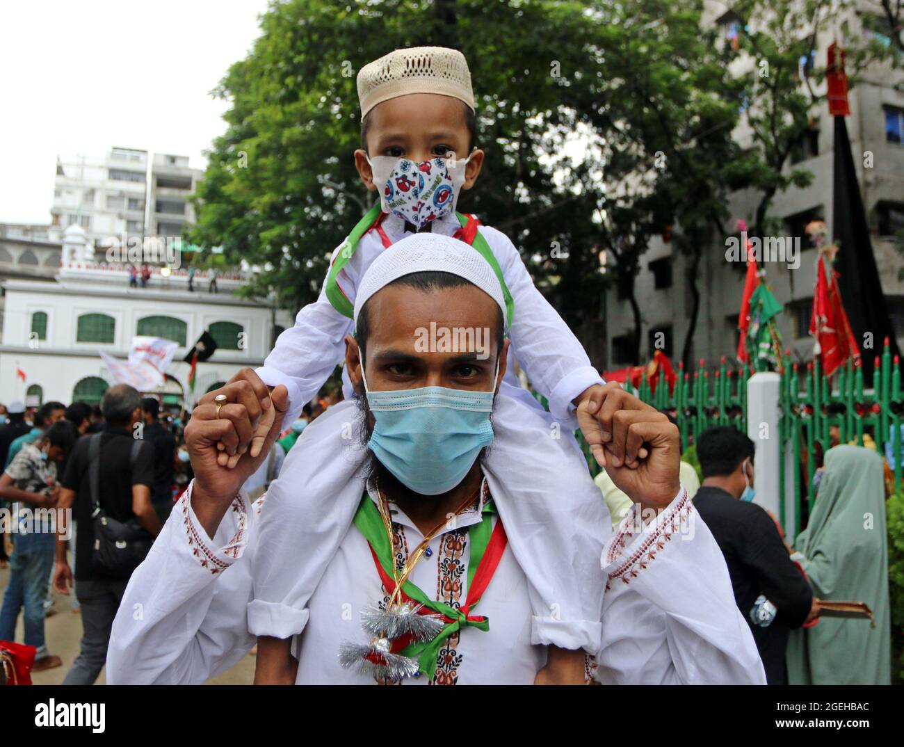 Non Exclusive: DHAKA, BANGLADESH - AUGUST 20: A shia man  lifts a child on their shoulders   during  the day of mourning to commemorate Ashura Day. Th Stock Photo