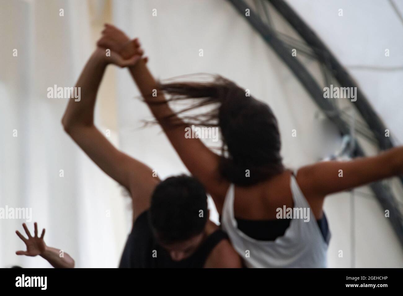 two dancers improvise in contact. Contemporary dance performing dancers' hands stretches into space against a background of natural greenery in contact improvisation intentionally with motion blur ond defocus bokeh Stock Photo