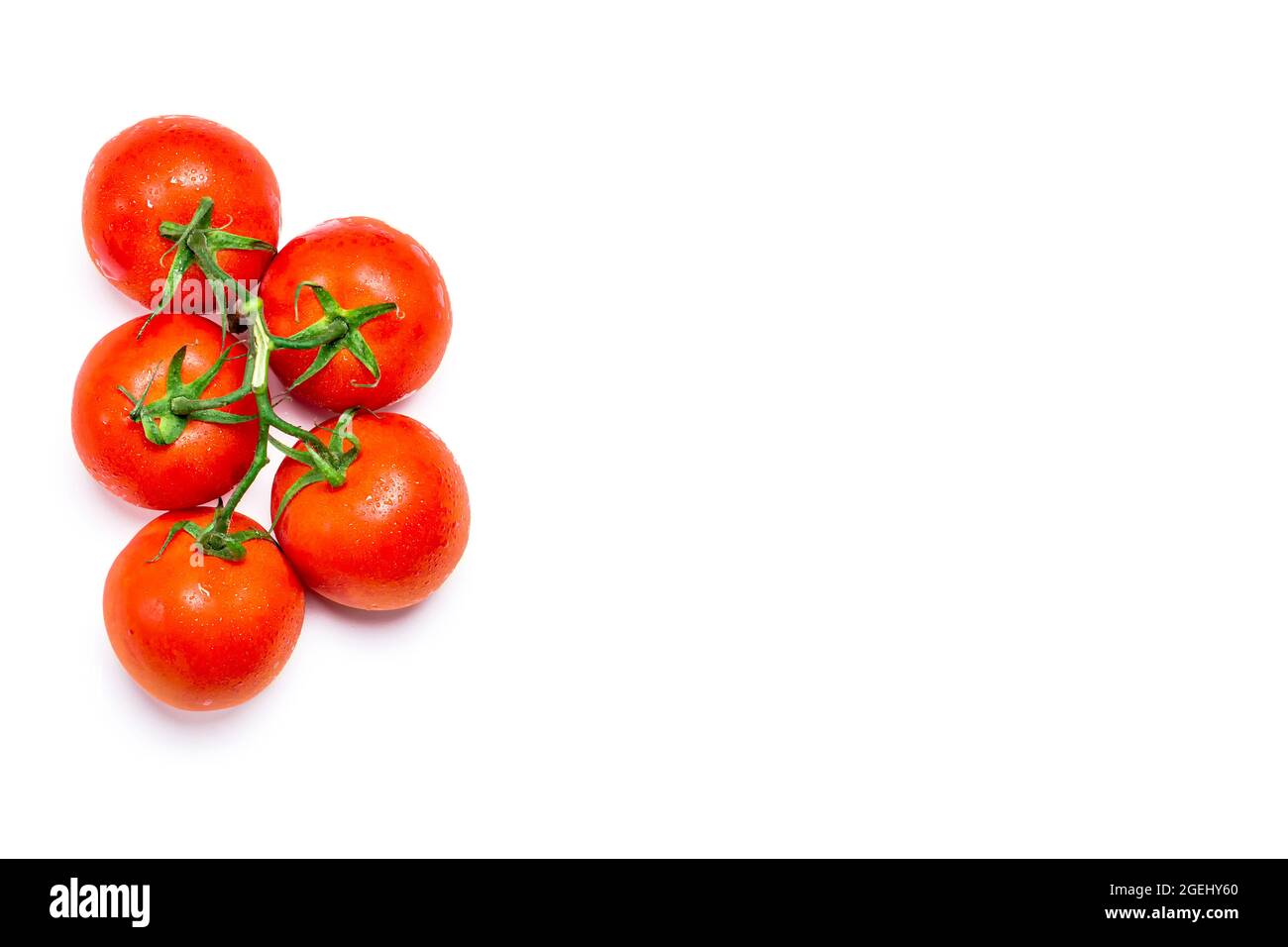 Overhead shot of five wet red natural tomatoes on a white background.The photo has copy space and is shot in horizontal format. Stock Photo