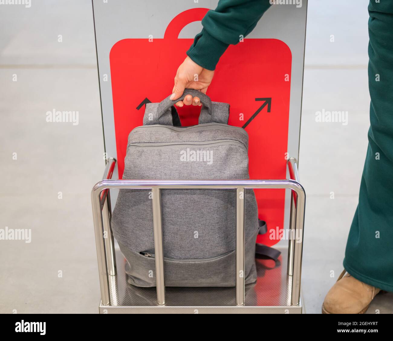 Woman checking backpack metal cage checking carry-on luggage at airport. Stock Photo