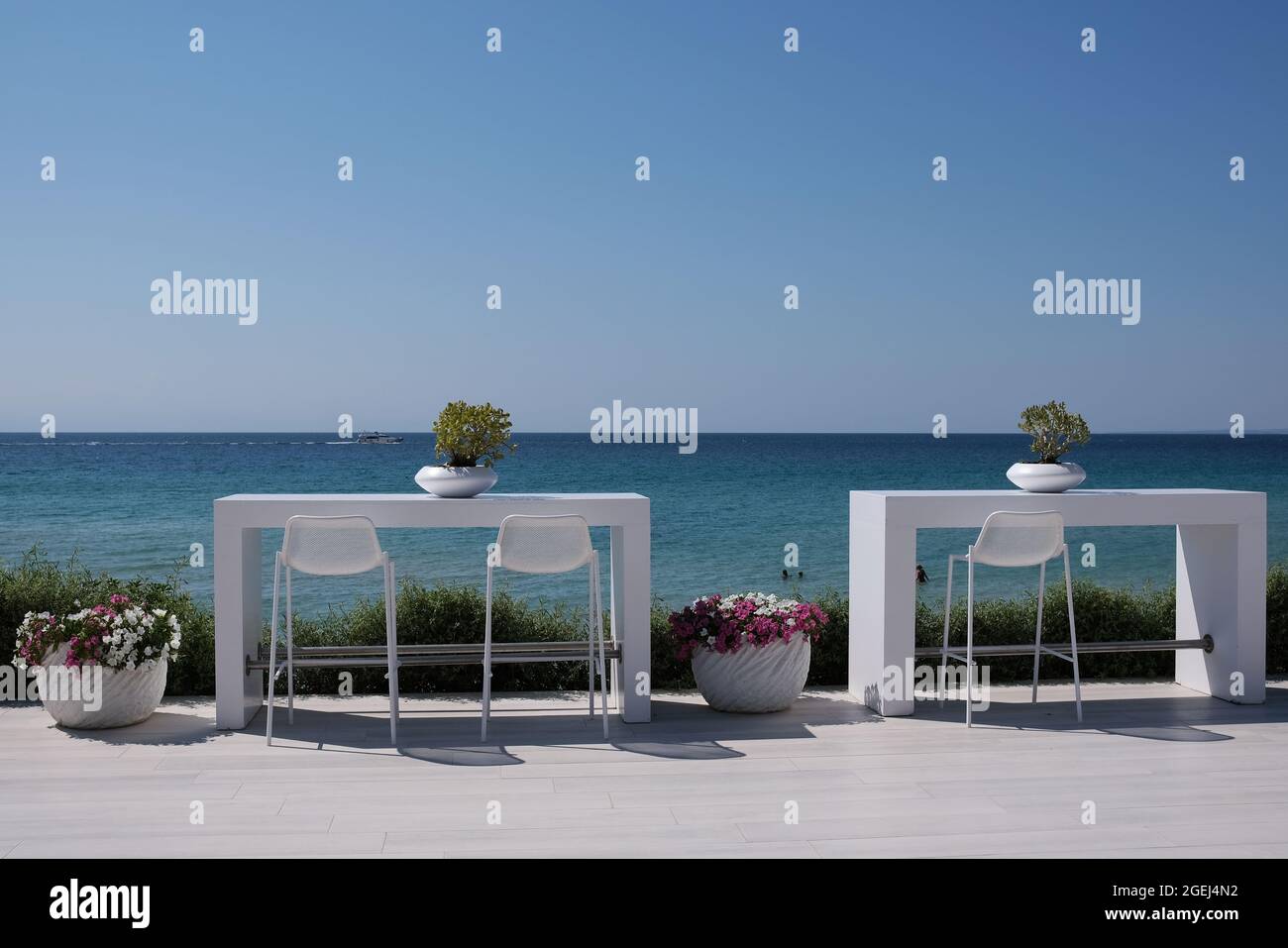 Beautiful decorated white table and chairs at an outdoor bar  in front of the aegean sea in Chalkidiki Greece Stock Photo