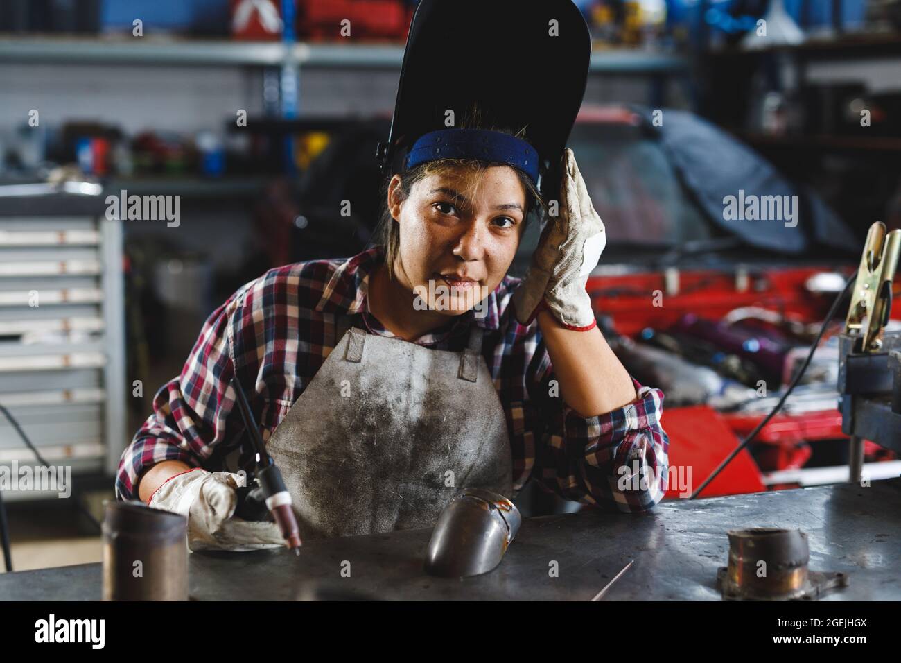 Mixed race female car mechanic welding car part in workshop Stock Photo