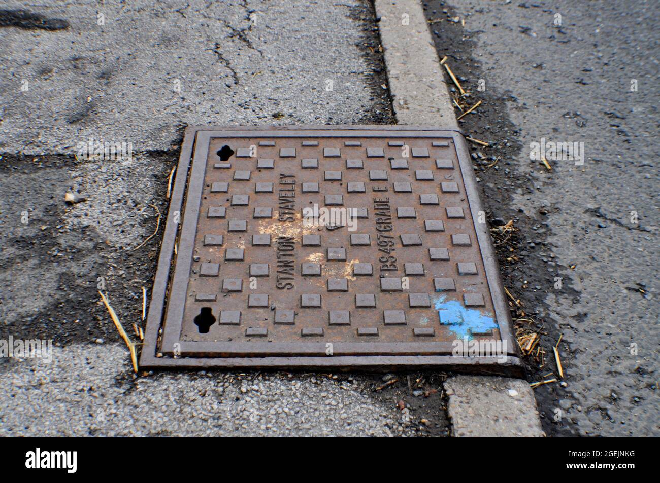 Man hole cover. A blue dot of spray paint on the corner indicates it has been inspected. Stock Photo