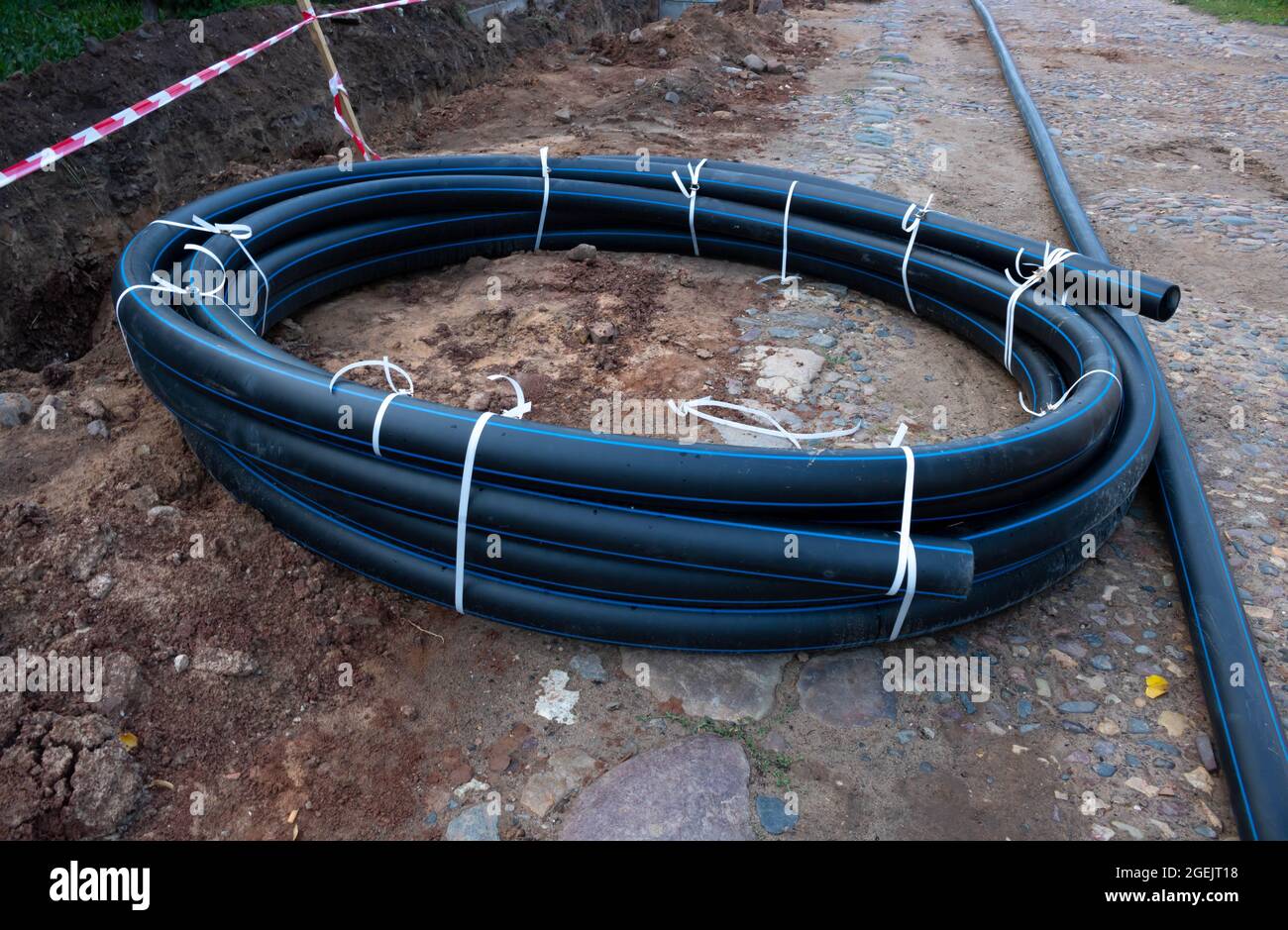 A circle of black plastic pipe lies on the ground. The concept of