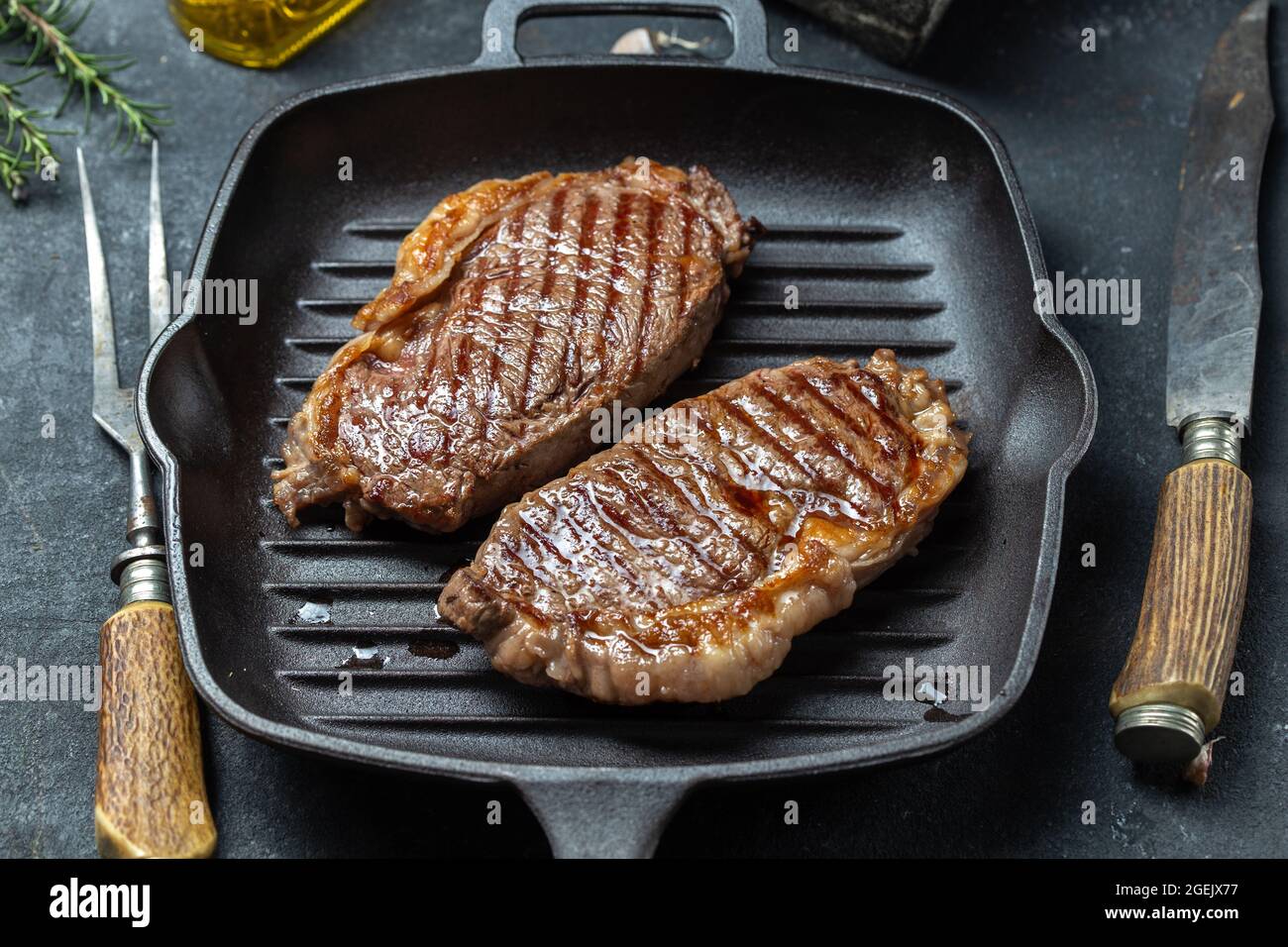 Fried strip loin steak on cast iron grill pan with olive oil and