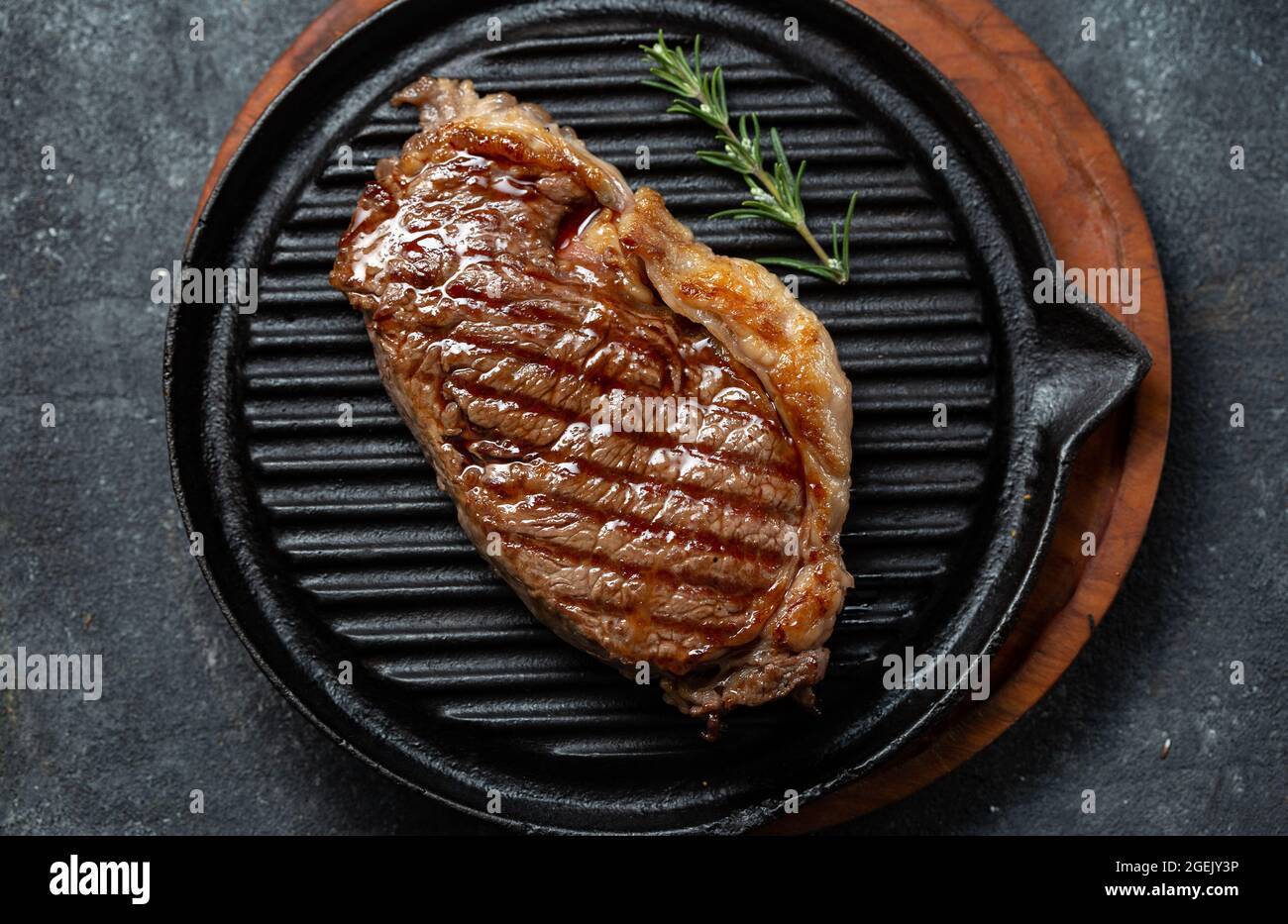 Fried strip loin steak on vintage cast iron grill pan and cutlery set