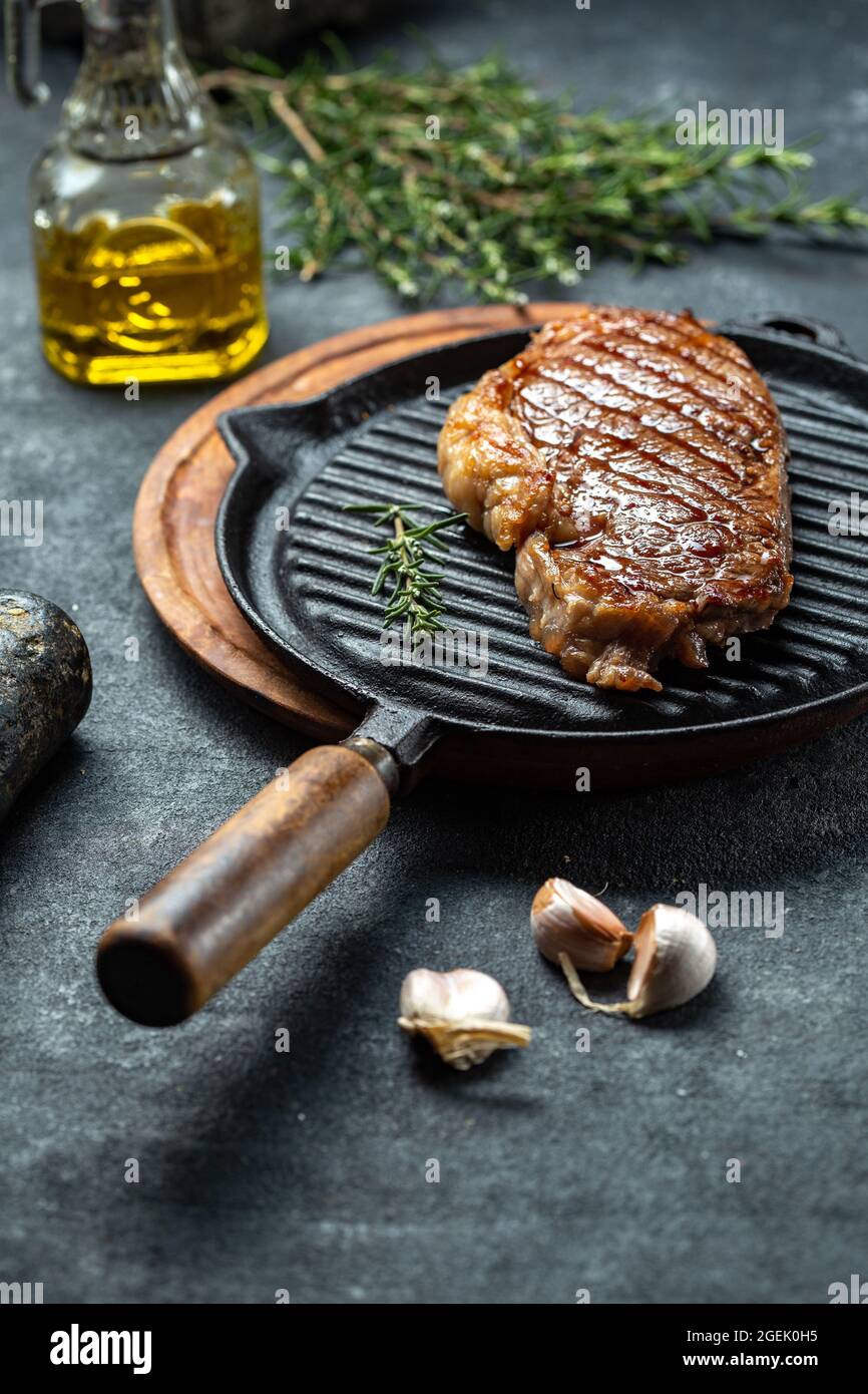 Fried strip loin steak on vintage cast iron grill pan and cutlery set