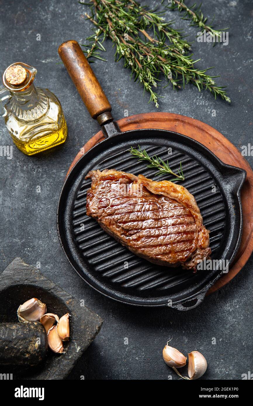 Fried strip loin steak on vintage cast iron grill pan and cutlery set