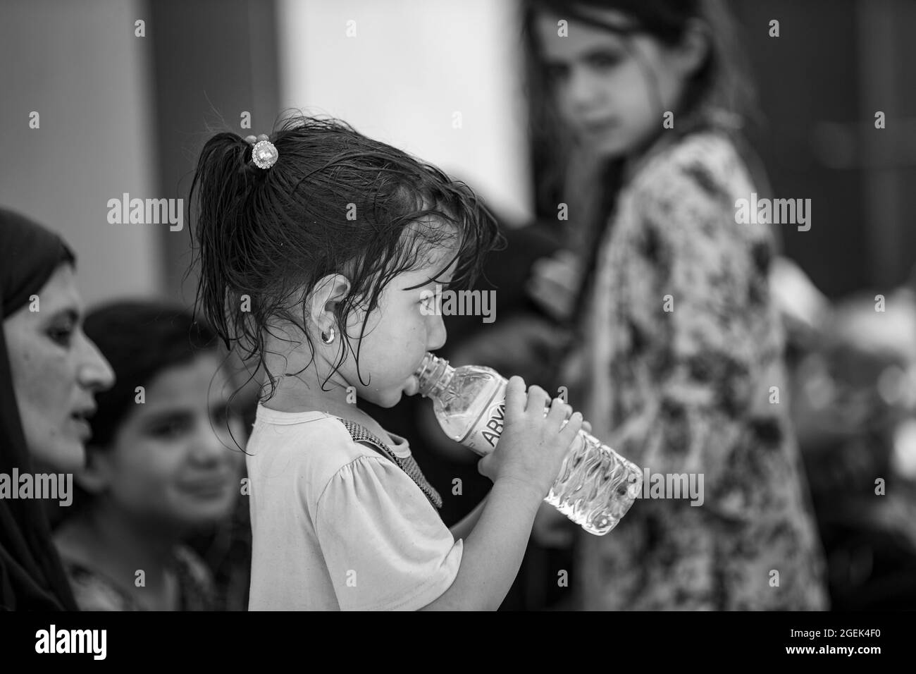 A child sips fresh water during an evacuation at Hamid Karzai International Airport, Kabul, Afghanistan, Aug. 20. U.S. service members are assisting the Department of State with an orderly drawdown of designated personnel in Afghanistan. (U.S. Marine Corps photo by Sgt. Samuel Ruiz). Stock Photo