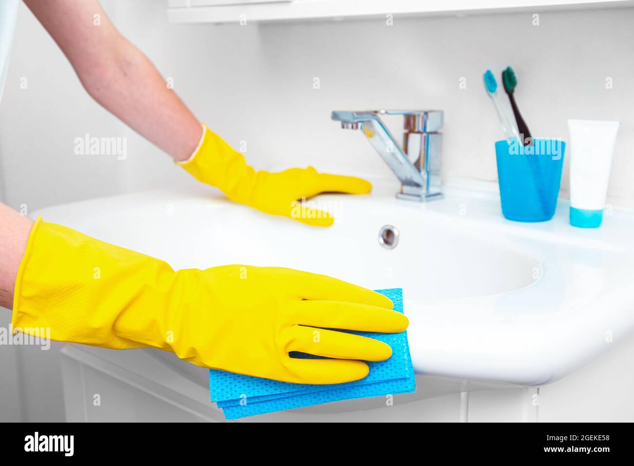 Woman doing chores in bathroom, cleaning of water tap or sink and faucet. Concept daily hygiene of bathroom Stock Photo