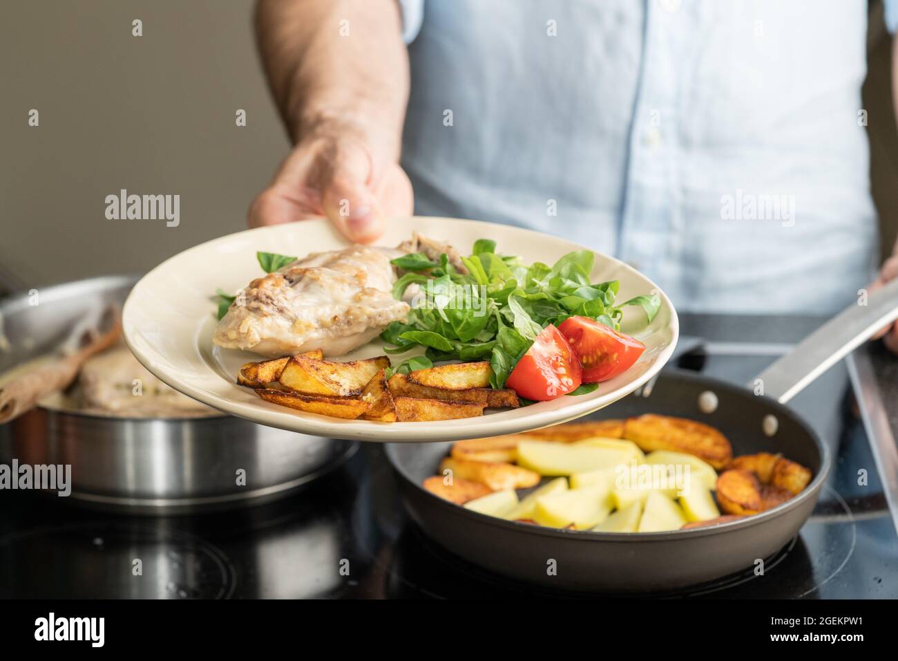 The hands of a man cook potatoes in a frying pan. Family dinner Stock