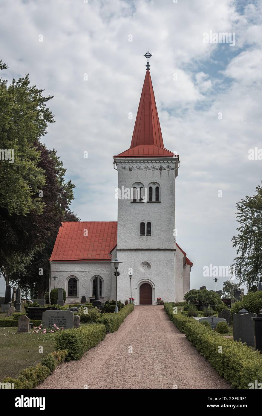 a white country church with a tall tower at the end of a long gravel path on a summer day, Stora Köpinge, Sweden, July 16, 2021 Stock Photo