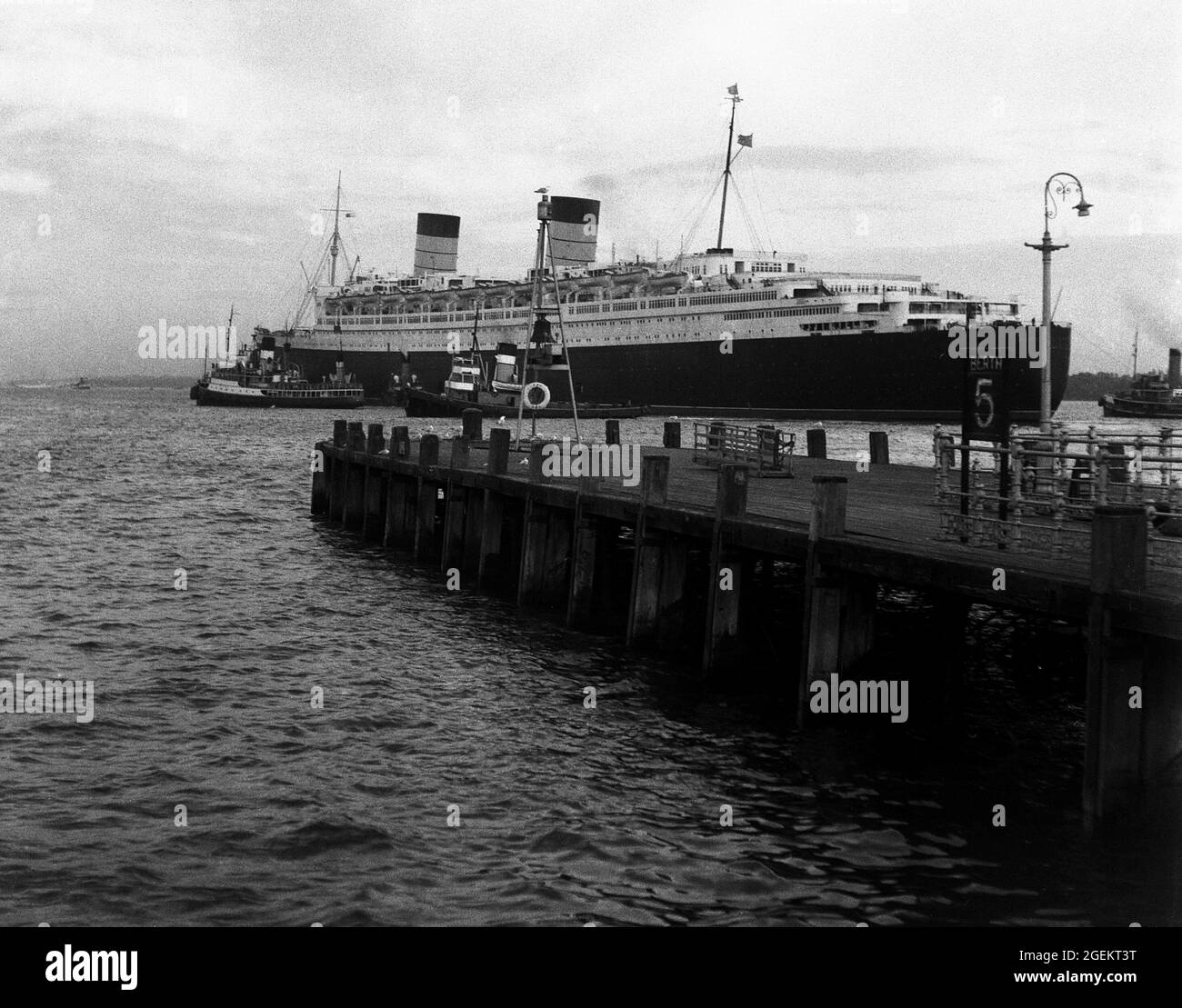 AJAXNETPHOTO. 1960S. SOUTHAMPTON, ENGLAND. - OUTWARD BOUND - CUNARD TRANSATLANTIC LINER RMS QUEEN ELIZABETH WITH TUGS IN ASSISTANCE, DEPARTS ON ONE OF HER REGULAR SCHEDULED SAILINGS TO NEW YORK.PHOTO:©SUSANNAH RITCHIE COLLECTION/AJAX REF:SR1960S 41 Stock Photo