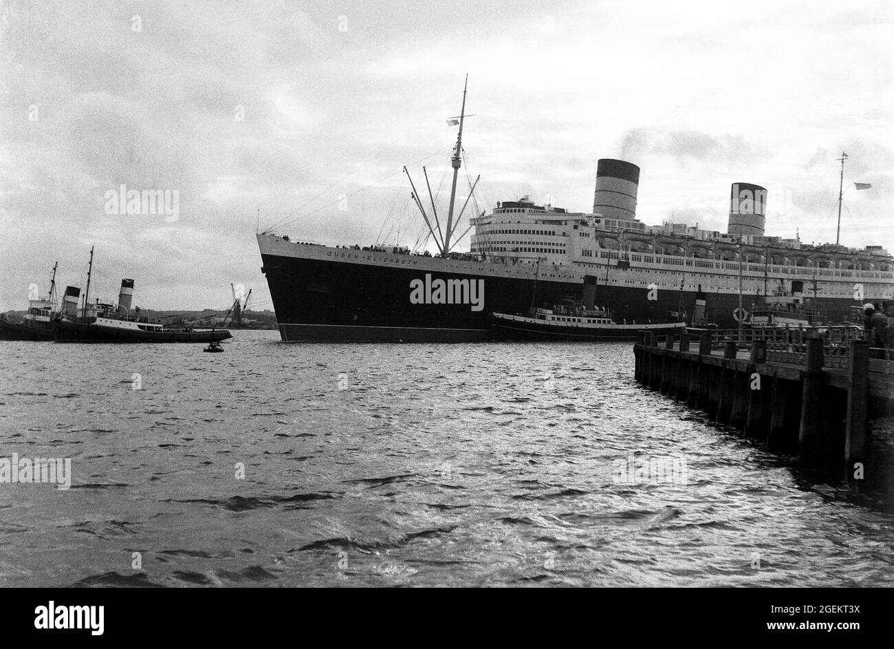AJAXNETPHOTO. 1960S. SOUTHAMPTON, ENGLAND. - OUTWARD BOUND - CUNARD TRANSATLANTIC LINER RMS QUEEN ELIZABETH WITH TUGS IN ASSISTANCE, DEPARTS ON ONE OF HER REGULAR SCHEDULED SAILINGS TO NEW YORK.PHOTO:©SUSANNAH RITCHIE COLLECTION/AJAX REF:SR1960S 42 Stock Photo