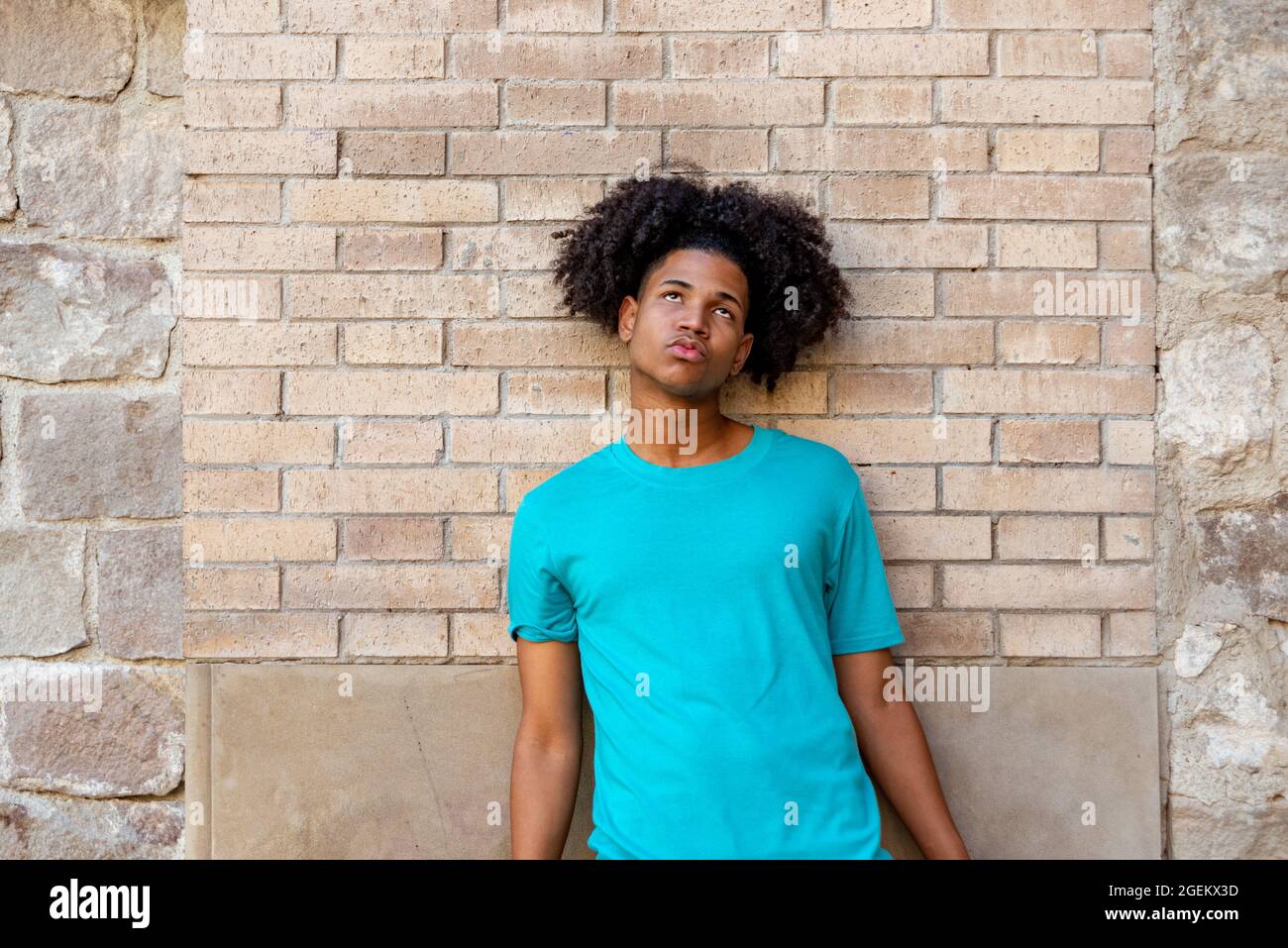 Afro latin male teenager against a wall, looking up. Stock Photo