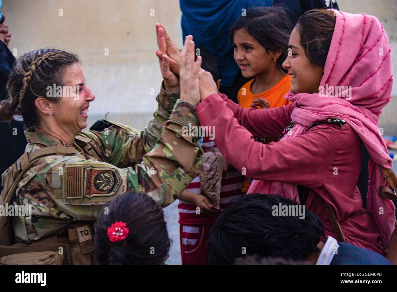 A U.S. Airman with the Joint Task Force-Crisis Response high fives child after helping reunite their family at Hamid Karzai International Airport, Afghanistan, Aug. 20. U.S. service members are assisting the Department of State with a Non-combatant Evacuation Operation (NEO) in Afghanistan. (U.S. Marine Corps photo by Cpl. Davis Harris) Stock Photo