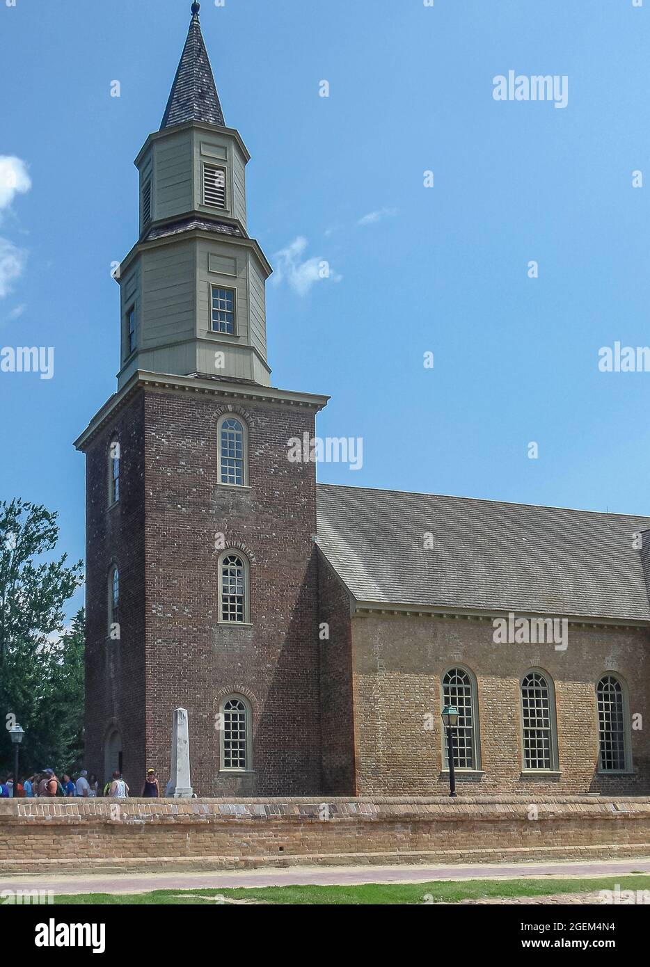 Williamsburg, VA, USA - June 20, 2006: Historic site. Bruton Episcopal parish church with focus on the tower against blue sky. Visitors in front of en Stock Photo