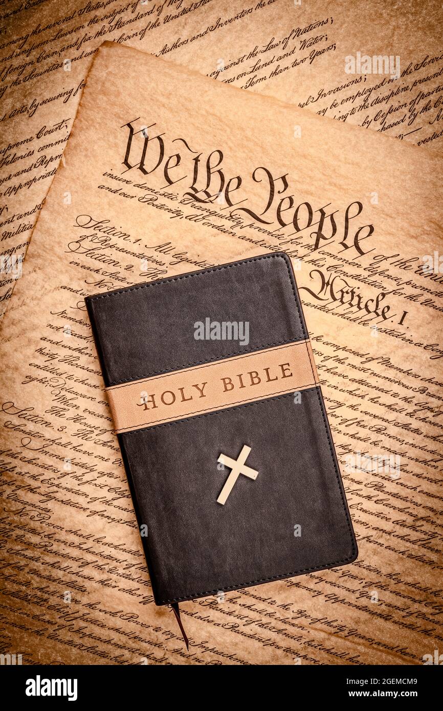 A holy bible and a small cross rest atop the United States Constitution, which is emblematic of freedom of religion without persecution. Stock Photo