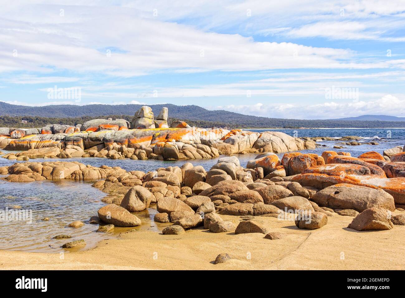 Granite boulders draped in orange lichen - Binalong Bay, Tasmania, Australia Stock Photo