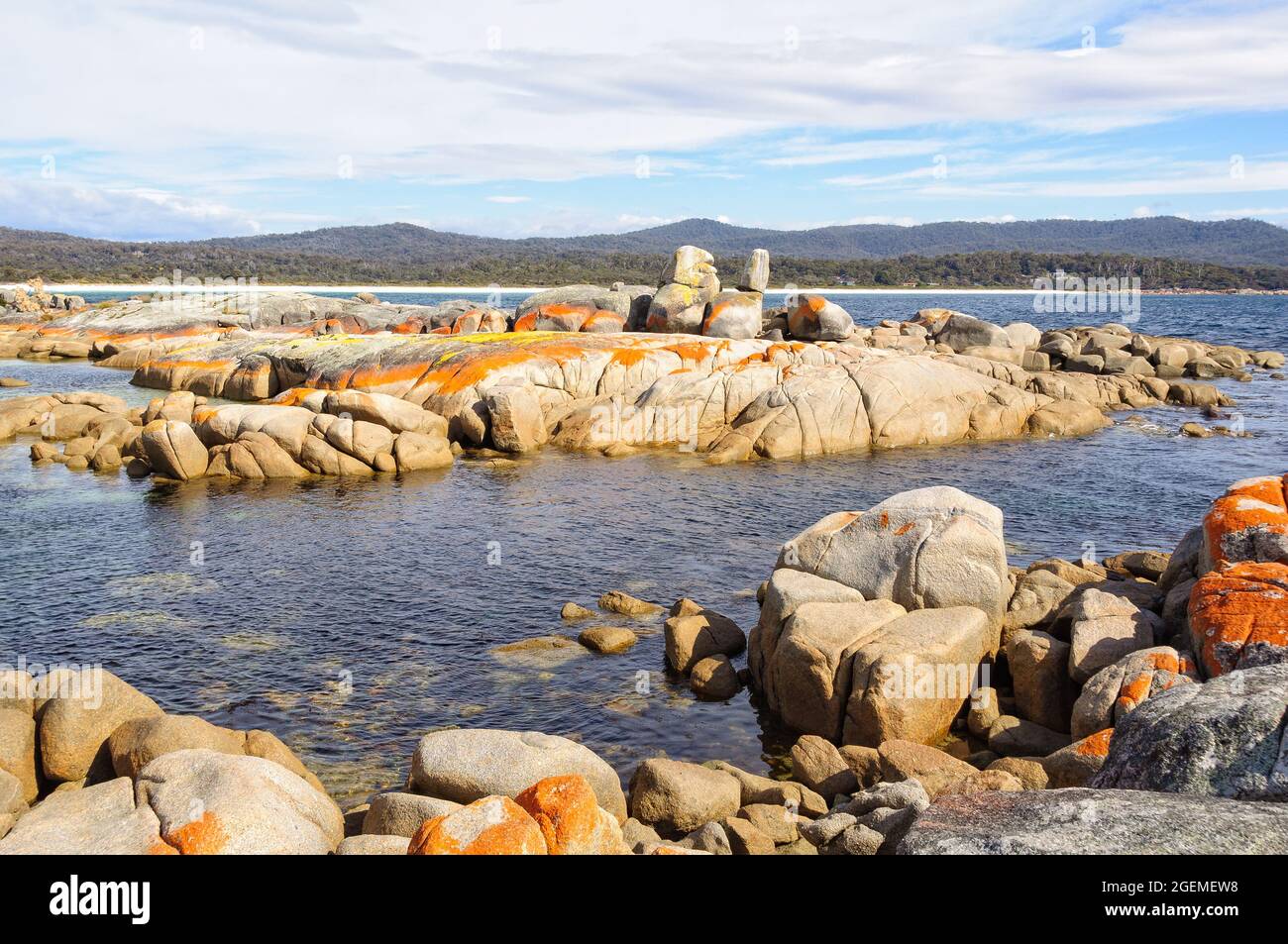 Granite boulders draped in orange lichen - Binalong Bay, Tasmania, Australia Stock Photo
