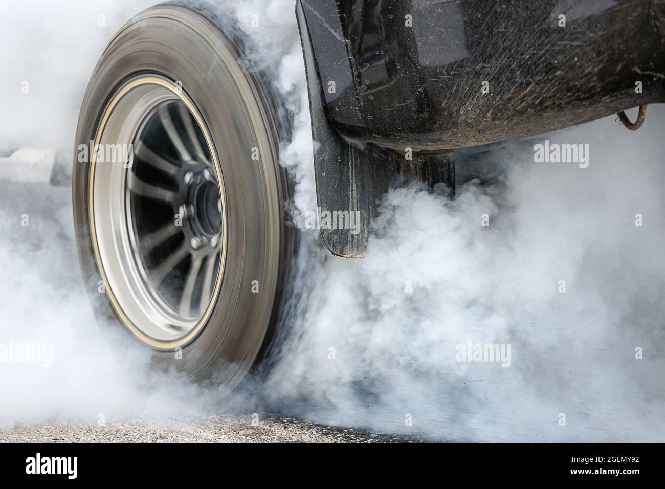 Drag racing car burns rubber off its tires in preparation for the race ...