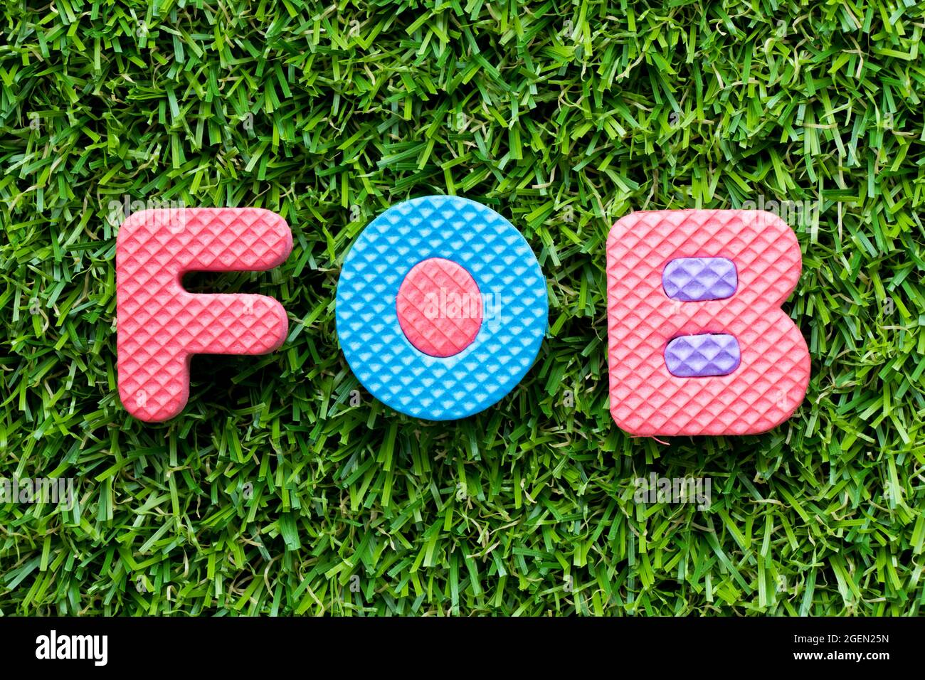 Color alphabet letter in word FOB (abbreviation of free on board) on artificial green grass