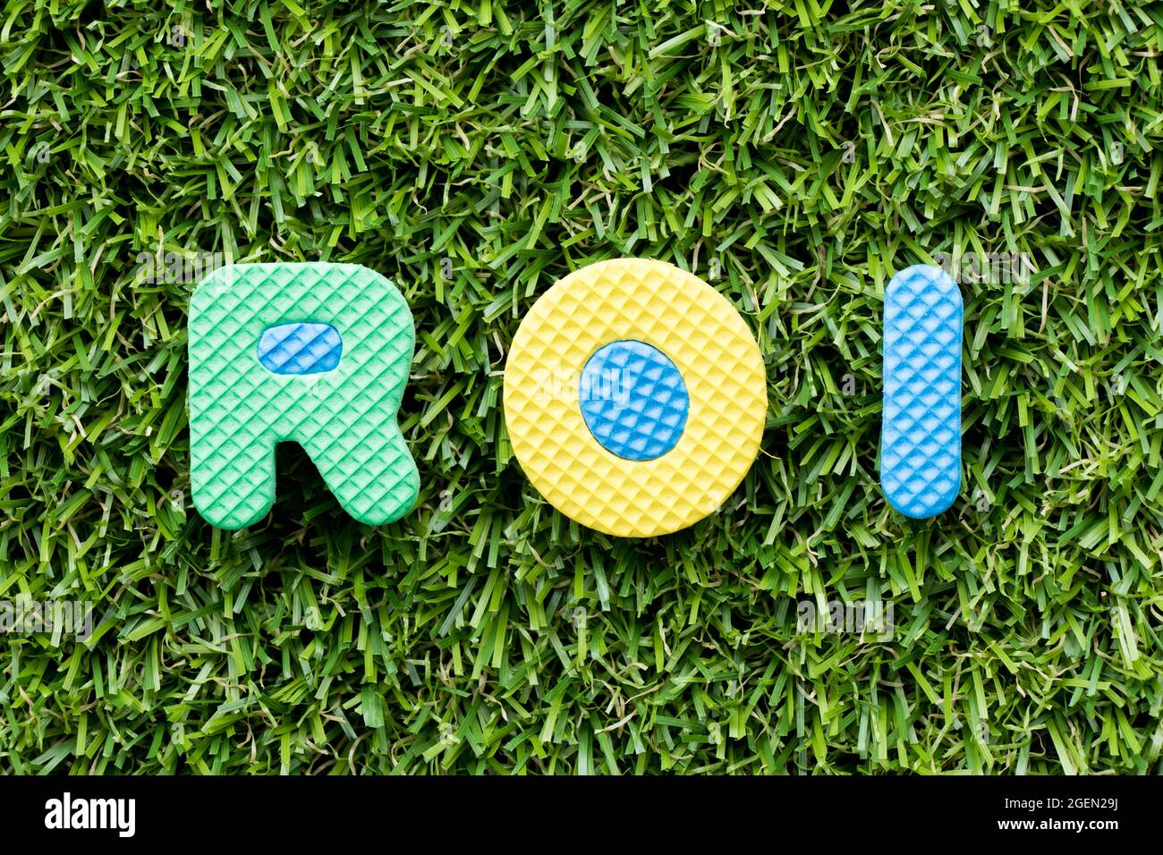 Color alphabet letter in word ROI (Abbbreviation of Return on Investment) on artificial green grass background Stock Photo