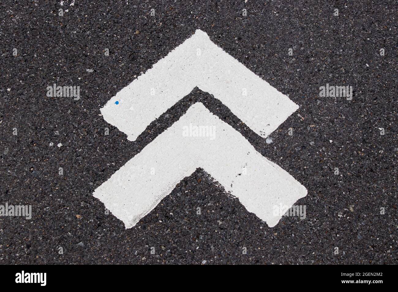 White painting in forward direction arrow symbol on black asphalt road ...