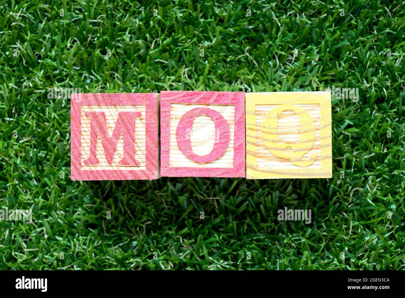 Color wood block in word MOQ (Abbreviation of Minimum Order Quantity) on artificial green grass
