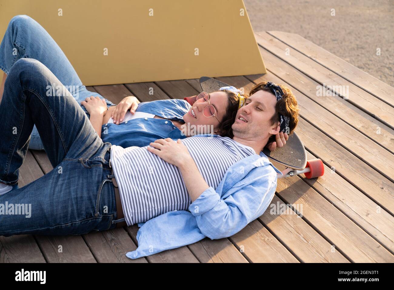 Dreamy couple lying on longboard relax outdoors together enjoy summer sunset. Relationship and love Stock Photo